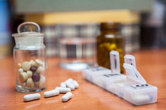 Old bottle of pills along with a few pills above a wooden table